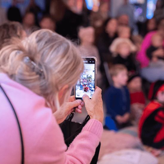 Sinterklaas op het My Jewellery Hoofdkantoor in 's-Hertogenbosch. Een vrouw maakt met haar mobiel een foto van kinderen die aan het kijken zijn naar de pieten show.