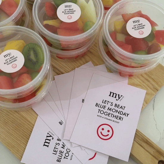 Bakjes fruit en een kaart waarop staat "Let's beat Blue Monday Together!" met een smiley.