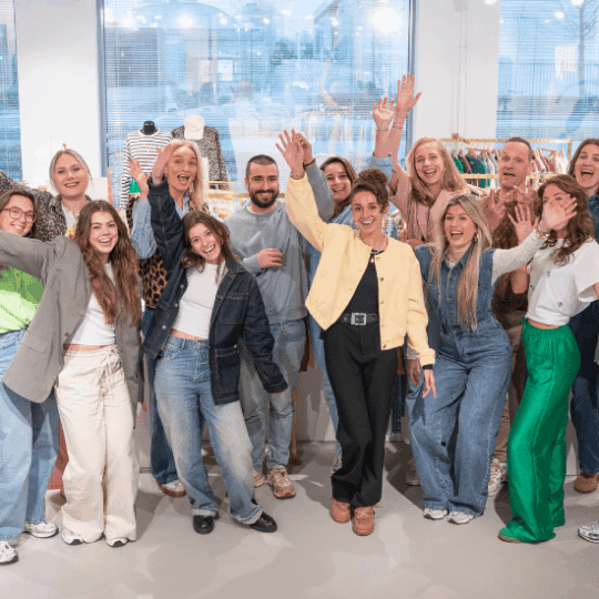 Dertien collega's in de My Jewellery showroom op het Hoofdkantoor in 's-Hertogenbosch die vrolijk hun handen omhoog doen