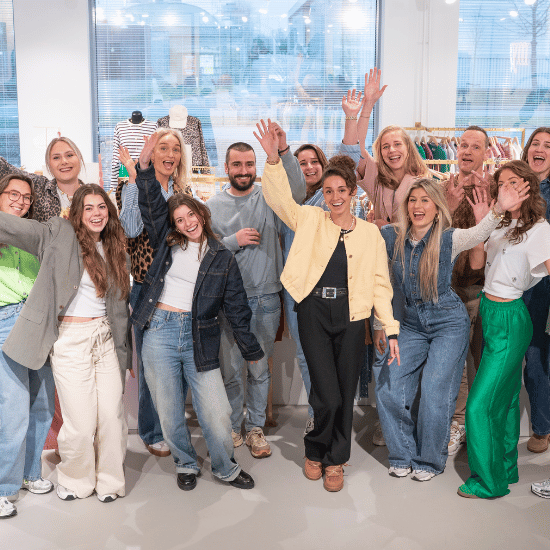 Dertien collega's in de My Jewellery showroom op het Hoofdkantoor in 's-Hertogenbosch die vrolijk hun handen omhoog doen