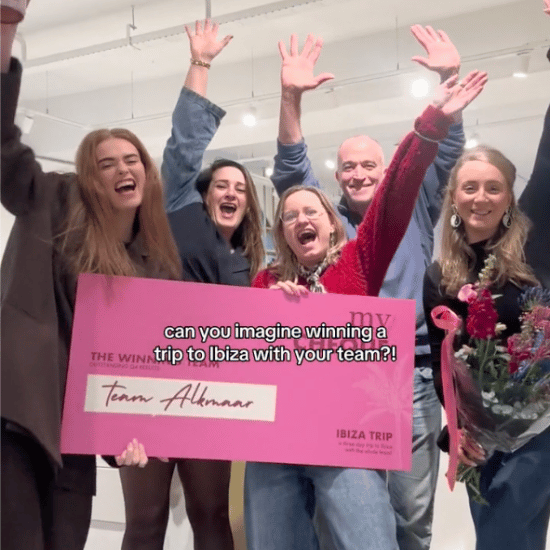 Het team van de Boutique in Alkmaar wint een trip naar Ibiza en vieren dit met een roze cheque en armen in de lucht