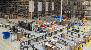 Overzichtsfoto van My Warehouse, het magazijn van My Jewellery, met de stellingen vol dozen op de achtergrond en de verpakmachine en sorteermachine op de voorgrond.