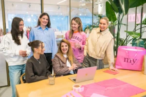 Zes My Jewellery collega's op het Hoofdkantoor in 's-Hertogenbosch die samen in een meeting ruimte zitten en er liggen verschillende verpakkingsmaterialen zoals tassen en stickers op tafel. Het gaat om team Branding op de foto