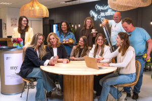 Gruppenfoto des Facilities-Teams in der My Jewellery Zentrale in ’s-Hertogenbosch. Zehn Kolleginnen und Kollegen sitzen und stehen gemeinsam um einen runden Tisch in der Bistro-Kantine. Sie lachen und tauschen sich miteinander aus.