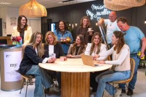 Groepsfoto van het Facilities team op het Hoofdkantoor van My Jewellery in 's-Hertogenbosch. Het zijn tien collega's die in de Bistro kantine om een ronde tafel zitten en staan. Ze lachen en overleggen met elkaar