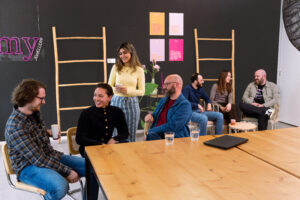 Groepsfoto van het Tech team op het Hoofdkantoor van My Jewellery in 's-Hertogenbosch. Er zitten zeven mensen in de kantine. Vier mensen staan linksvoor met elkaar te praten aan een tafel. Drie mensen zitten rechtsachter op comfortabele stoelen met elkaar te praten