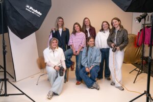 Groepsfoto van het Productfotografie team op het Hoofdkantoor van My Jewellery in 's-Hertogenbosch. Er staan zeven mensen in de styleshoot met studiolampen en een witte achtergrond. Sommige hebben camera's in hun handen en ze kijken lachend naar de camera.