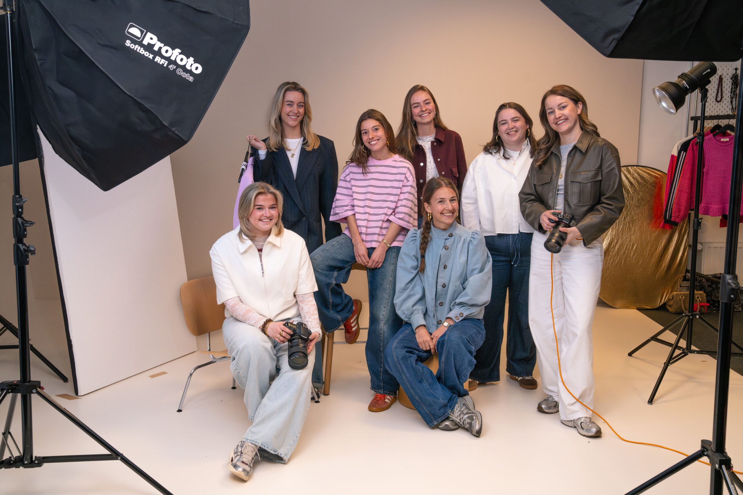 Groepsfoto van het Productfotografie team op het Hoofdkantoor van My Jewellery in 's-Hertogenbosch. Er staan zeven mensen in de styleshoot met studiolampen en een witte achtergrond. Sommige hebben camera's in hun handen en ze kijken lachend naar de camera.