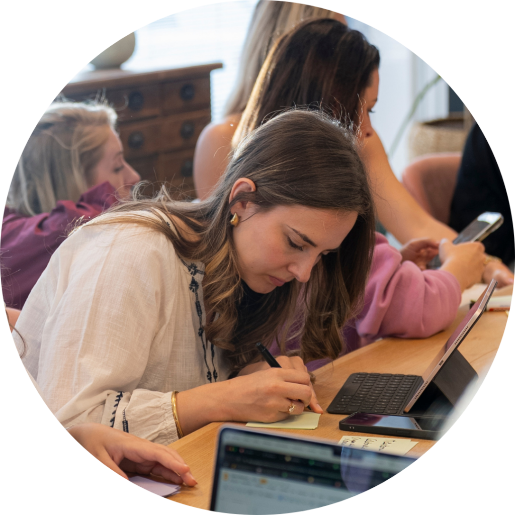 Foto van het Sales team op het Hoofdkantoor van My Jewellery in 's-Hertogenbosch. Er zitten een aantal mensen aan een tafel te overleggen. De focus ligt op een dame die aan het schrijven is op een post it.