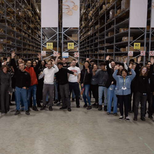 Teamfoto van My Warehouse van My Jewellery in 's-Hertogenbosch. Er staan tientallen mensen net hun handen omhoog voor een zestal stellingen
