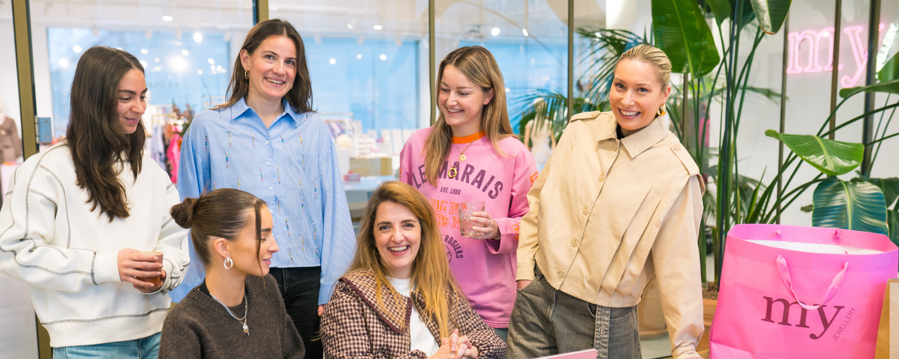 Zes My Jewellery collega's op het Hoofdkantoor in 's-Hertogenbosch die samen in een meeting ruimte zitten en er liggen verschillende verpakkingsmaterialen zoals tassen en stickers op tafel. Het gaat om team Branding op de foto