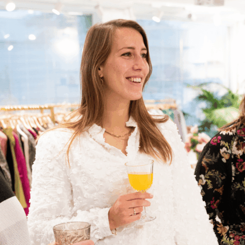 Jasmijn Besselink, Workplace Experience Coördinator, lachende foto in de showroom met een glas jus d'orange in haar hand
