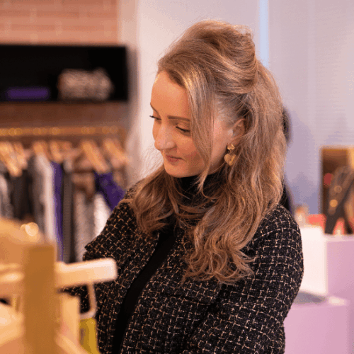 Megan van Eenennaam, Area Manager, foto in de showroom terwijl ze door de kledingrekken kijkt